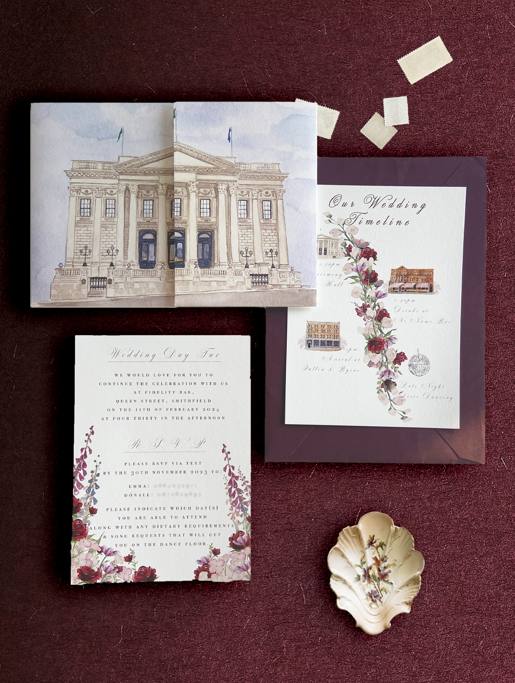 A wedding invitation suite featuring a gatefold invitation with a watercolour illustration of Dublin City Hall, and details card with watercolour detailing paired with a claret envelope, by Hannah Blake Art