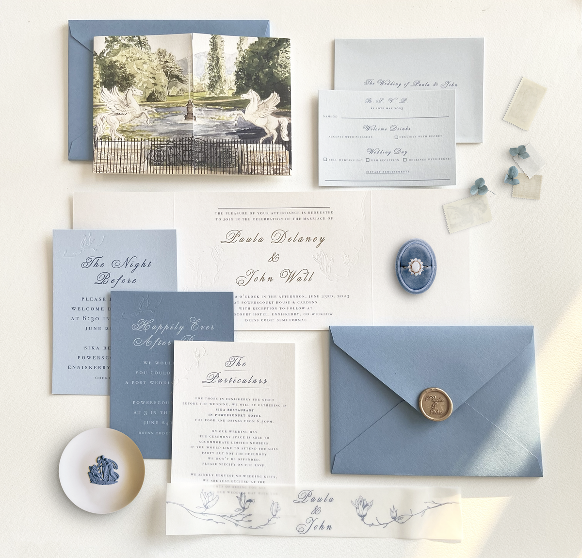 A wedding invitation suite featuring a gatefold invitation with a watercolour illustration of Powerscourt Estate's Italian Garden Fountain, paired with a cornflower blue envelope, by Hannah Blake Art